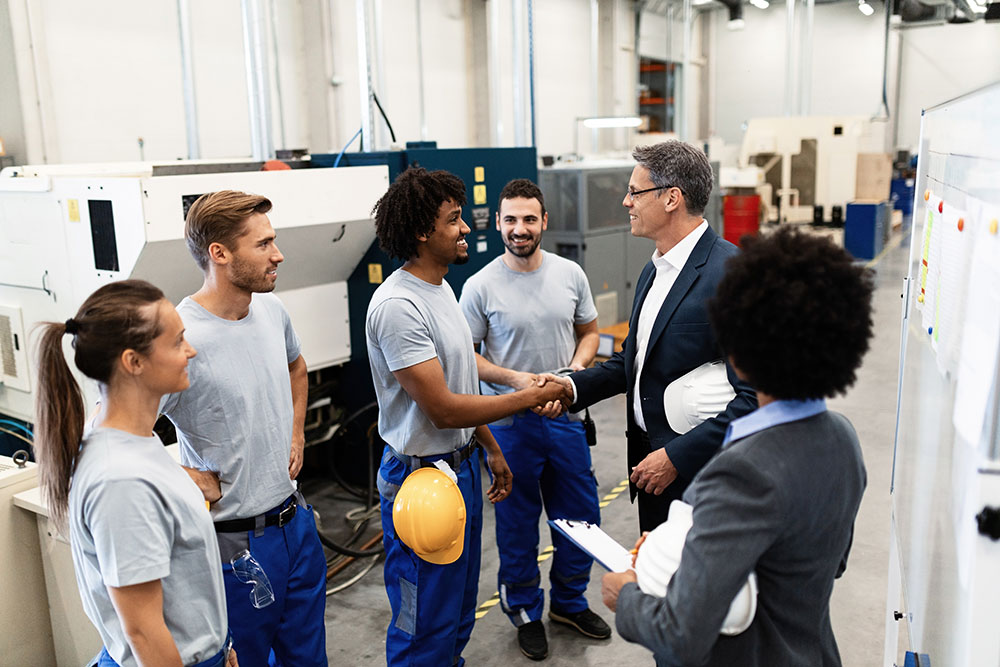 Company manager greeting with new manufacturing employees during a tour of factory. Credit: Drazen Zigic iStockphoto LP