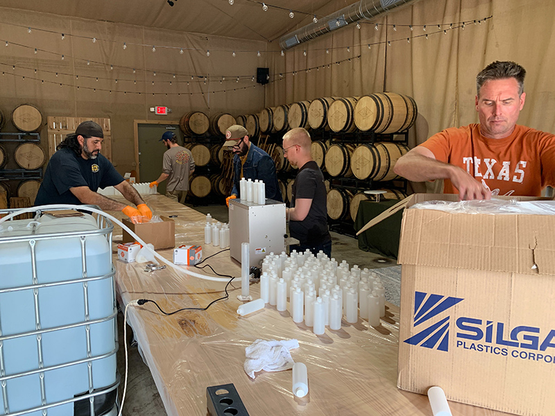 Desert Door Texas Sotol employees unpack materials and bottle hand sanitizer produced at their distillery in Driftwood, Texas.