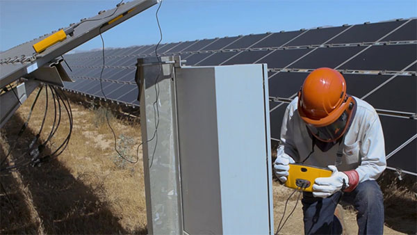 A worker performs curve trace testing, a critical skill taught in clean energy apprenticeship programs to optimize solar panel efficiency.