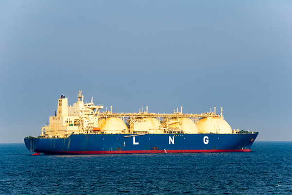 Blue colored hull large liquefied natural gas (LNG) carrier with 4 LNG tanks sails along the sea.