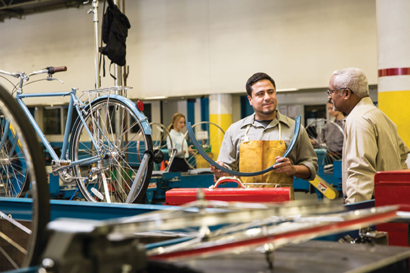 two workers talking looking at bicycle parts